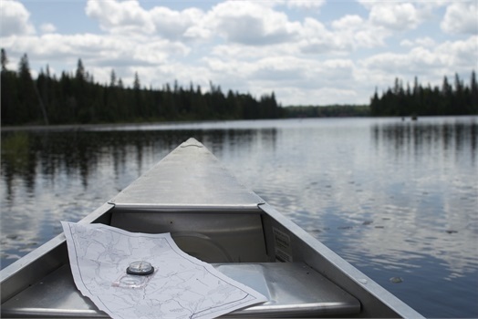 canoe with map and compass floating on lake