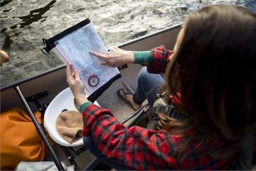 woman in canoe pointing to map she is holding